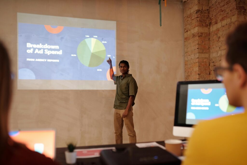 Young man delivering a business presentation on ad spend with charts and graphs in a modern office setting.