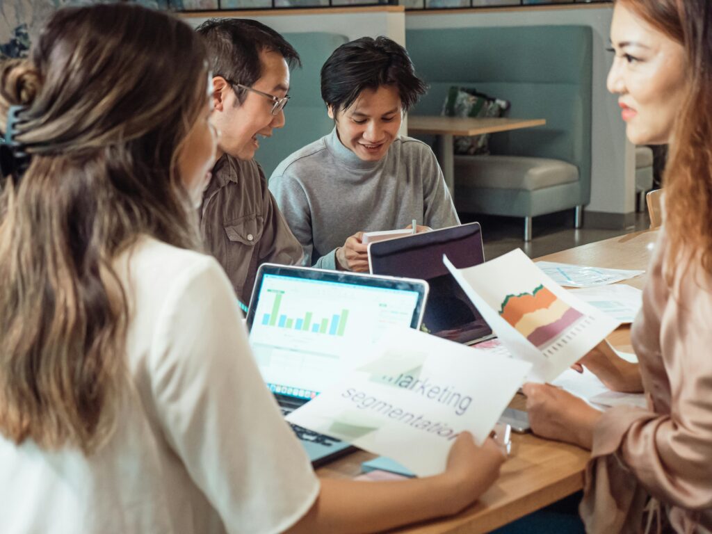 Group of colleagues discussing marketing strategies with charts and laptops in an office setting.